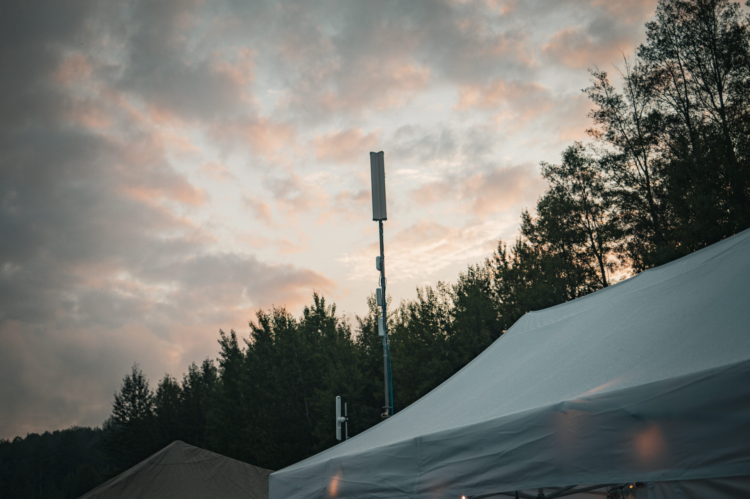 A tall satellite tower stands next to a white tent